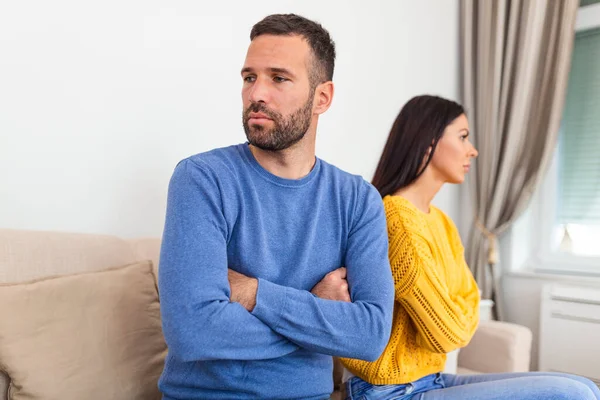 Unhappy couple not talking after an argument at home . unhappy couple not speaking after having argument. Young couple in fight with arms crossed sitting on couch after quarrel at home.