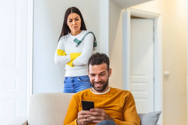 Jealous girlfriend tries to peep at boyfriends smart phone, feels sad as he texts with someone, dressed in casual sweaters, have troubles with relationships.