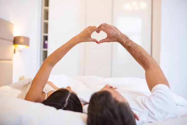 Coppia Sdraiata Sul Letto Formando Forma Cuore Con Mano — Foto Stock