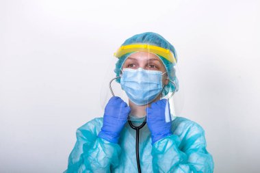 Doktor, hemşire Covid-19 Coronavirus 'la savaşırken beyaz arka planda nasıl korunacağını göster. Tam korumalı yüz kalkanıyla steteskopunu takan bir sağlık görevlisi.