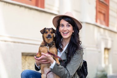 Genç ve çekici bir kadın, sokak ortasında köpeğiyle oynuyor. Yaşam tarzı insan konsepti. Köpeğiyle dışarıda oynayan güzel kadın.