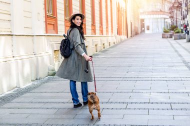 Genç ve çekici bir kadın, sokak ortasında köpeğiyle oynuyor. Yaşam tarzı insan konsepti. Köpeğiyle dışarıda oynayan güzel kadın.