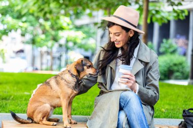 Güzel, genç bir kadın köpeğiyle dışarıda parkta oynuyor. Yaşam tarzı portresi. Sevimli genç bir kadın yavru köpeğini kucaklıyor. Sahibi ve köpeği arasında aşk.