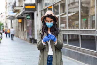 Coronavirus COVID-19 ve hava kirliliğini önlemek için yüz koruyucu maske takan genç bir kadın.