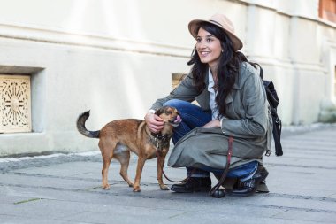 Genç ve çekici bir kadın, sokak ortasında köpeğiyle oynuyor. Yaşam tarzı insan konsepti. Köpeğiyle dışarıda oynayan güzel kadın.