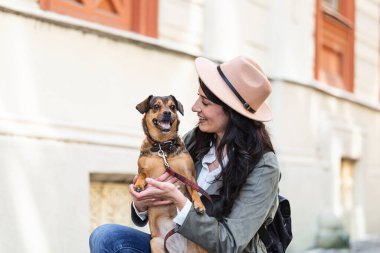 Genç ve çekici bir kadın, sokak ortasında köpeğiyle oynuyor. Yaşam tarzı insan konsepti. Köpeğiyle dışarıda oynayan güzel kadın.