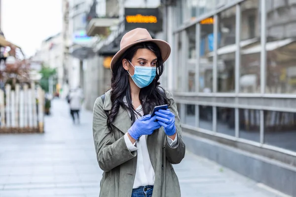 Portrait of a young woman wile wearing a face mask for protection from cold and flu and viruses. Young woman with face mask in the street. Woman wearing face mask because of air pollution in the city