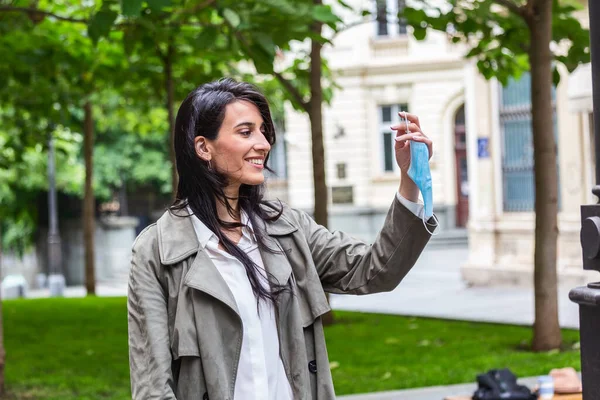 Woman throwing away her mask. young happy girl looking at protective medical mask, take off remove mask from her face. End of pandemic coronavirus concept. NCoV, Covid 19. Pollen allergy at spring