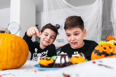 Cadılar bayramında eğlenen çocuklar etrafı korkunç süslemelerle çevrili. Jack O 'Lantern Cadılar Bayramı balkabağı ve çörekler masada. Mutlu Cadılar Bayramı!