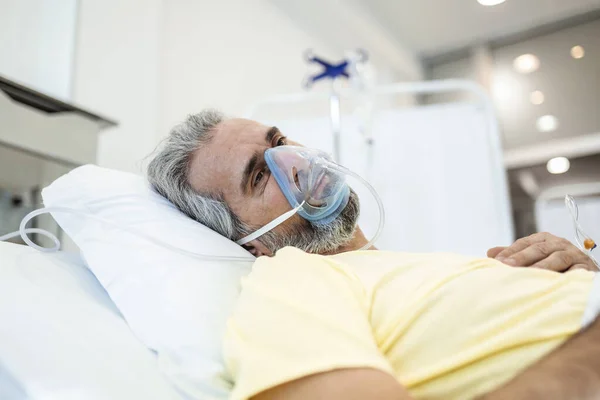 Portrait of an elderly patient, with oxygen mask, in a hospital bed. Man in bed with oxygen mask in hospital, Healthcare workers in the Coronavirus Covid19 pandemic