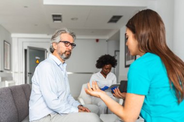 Hastanenin bekleme odasında bir doktora danışıyorum. Hasta oturuyor. Teşhis, hastalıkların önlenmesi, sağlık hizmetleri, sağlık hizmetleri, danışmanlık veya eğitim, sağlıklı yaşam tarzı kavramı