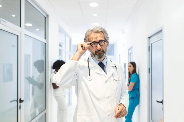 Portrait Confident Mature Doctor Holding His Glasses Hospital Corridor Wearing — Stockfoto