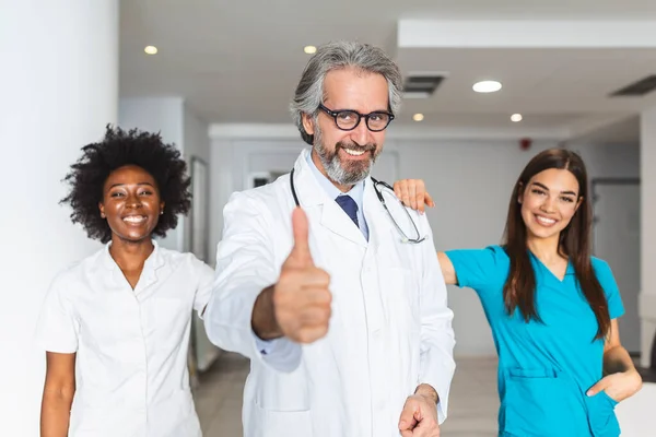 clinic, profession, people, health care and medicine concept - happy group of medics or doctors at hospital corridor. Group of doctors at the hospital hall - healthcare and medicine concept