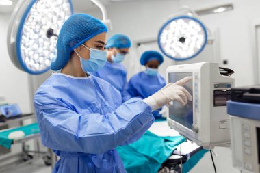 Anestezi uzmanı kalp ameliyatı sırasında vücudun hayati fonksiyonlarını takip ediyor. Cerrah ameliyat sırasında tıbbi monitöre bakıyor. Doktor hasta sağlığı durumunu kontrol ediyor..