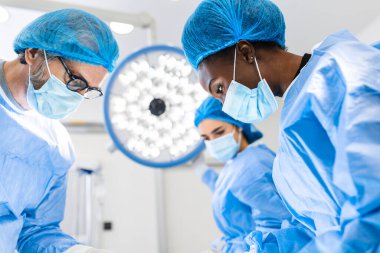 Team of professional doctors performing operation in surgery room. Medical Team Performing Surgical Operation in Bright Modern Operating Room