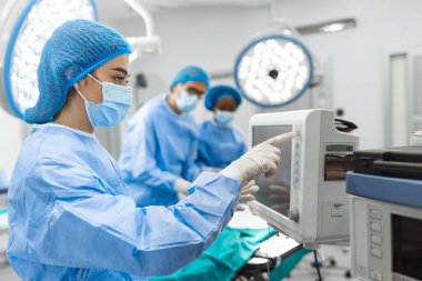 Anestezi uzmanı kalp ameliyatı sırasında vücudun hayati fonksiyonlarını takip ediyor. Cerrah ameliyat sırasında tıbbi monitöre bakıyor. Doktor hasta sağlığı durumunu kontrol ediyor..