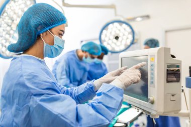Anestezi uzmanı kalp ameliyatı sırasında vücudun hayati fonksiyonlarını takip ediyor. Cerrah ameliyat sırasında tıbbi monitöre bakıyor. Doktor hasta sağlığı durumunu kontrol ediyor..