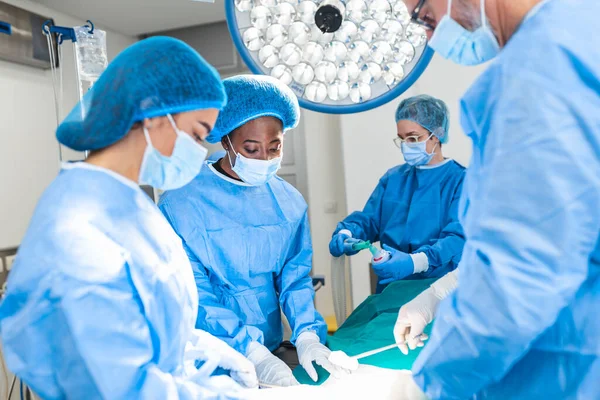 Group of surgeons wearing safety masks performing operation. Medicine concept. surgery, medicine and people concept - group of surgeons at operation in operating room at hospital