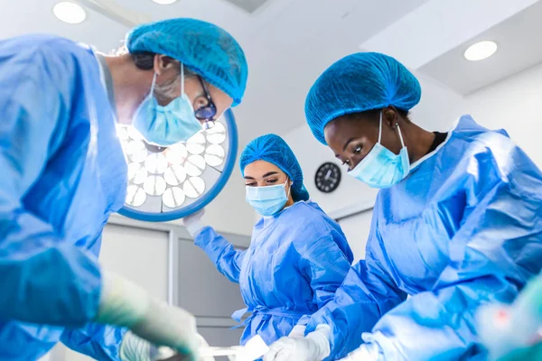 Medical team performing operation. Group of surgeon at work in operating theatre toned in blue. Doctor operation in operation room at hospital concept for insurance advertising.