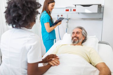 Healthcare concept of professional doctor consulting and comforting elderly patient in hospital bed or counsel diagnosis health. Medical doctor or nurse holding senior patient's hands and comforting him