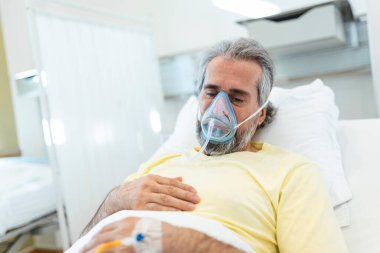 Portrait of retired senior man breathing slowly with oxygen mask during coronavirus covid-19 outbreak. Old sick man lying in hospital bed, getting treatment for deadly infection