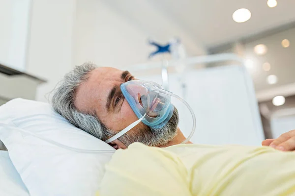 Portrait of an elderly patient, with oxygen mask, in a hospital bed. Man in bed with oxygen mask in hospital, Healthcare workers in the Coronavirus Covid19 pandemic