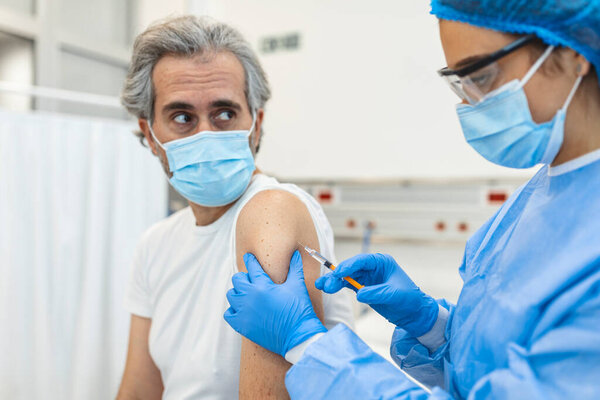 An elderly man receiving the injection of the coronavirus vaccine by a doctor to receive the antibodies, immunize the population. side effects, risk people, antibodies, new normal, covid-19.