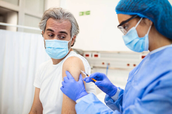 An elderly man receiving the injection of the coronavirus vaccine by a doctor to receive the antibodies, immunize the population. side effects, risk people, antibodies, new normal, covid-19.