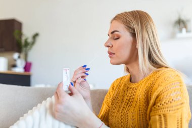 Young woman holding self testing self-administrated swab and medical tube for Coronavirus covid-19, before being self tested at home