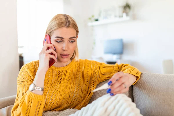 Young Woman Looking Thermometer She Has Fever Calling Her Doctor — Stockfoto