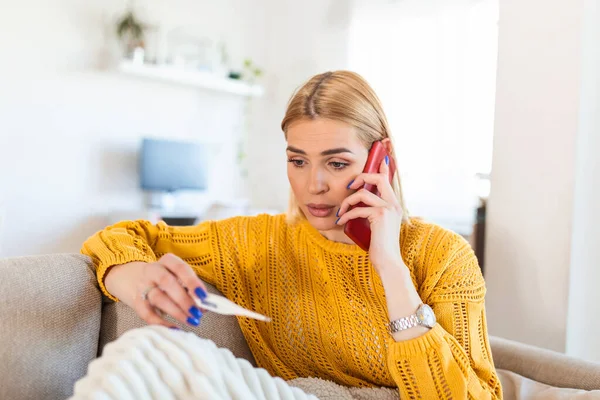 Young Woman Looking Thermometer She Has Fever Calling Her Doctor — Stockfoto