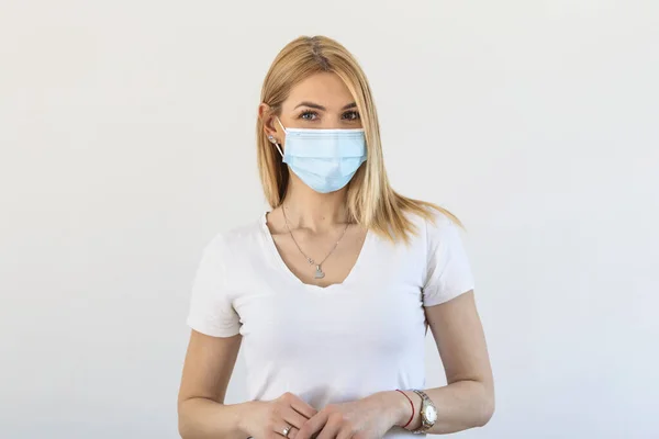 Girl in respiratory mask. Masked woman looks at camera. Cold, flu, virus, tonsillitis, respiratory disease, quarantine, epidemic concept. Beautiful caucasian young woman with disposable face mask