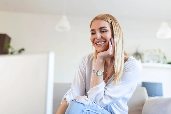 Beautiful woman freelancer noting information for planning project doing remote job via laptop computer. Girl laughing while reading email on modern laptop device .