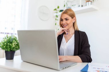 Portrait of happy young woman looking at laptop working at home. Successful lady laughing and working at home. Beautiful stylish woman smiling and working at home.