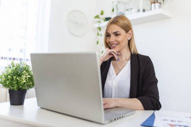 Portrait of happy young woman looking at laptop working at home. Successful lady laughing and working at home. Beautiful stylish woman smiling and working at home.