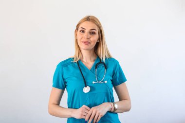 Hastanede çalışan genç bir kadın doktor ve tıbbi personel. Hemşire ayağa kalkar ve gülümser. Ameliyat önlüğü ve steteskop takar..