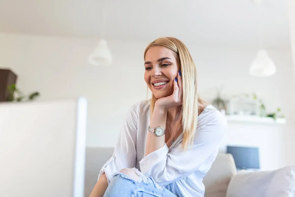 Beautiful woman freelancer noting information for planning project doing remote job via laptop computer. Girl laughing while reading email on modern laptop device .