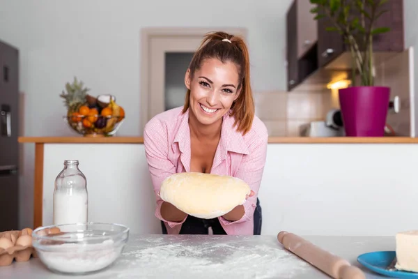 Young woman knead dough at kitchen, homemade bakery making. Woman kneading dough on kitchen table