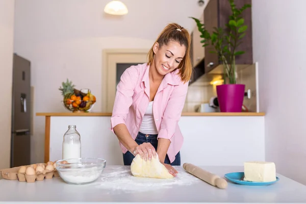 Young woman knead dough at kitchen, homemade bakery making. Woman kneading dough on kitchen table