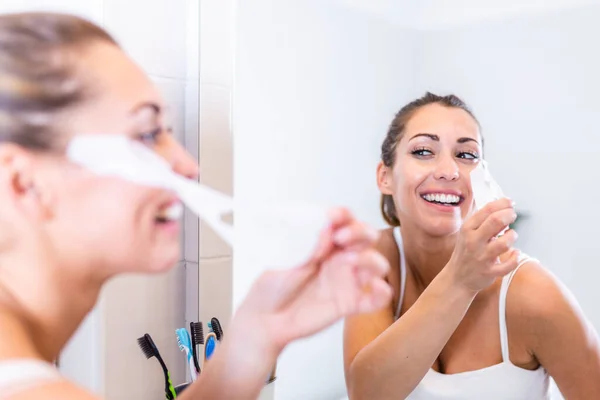 Frau Blickt Spiegel Und Zieht Kosmetikmaske Gesichtsreinigung Hause Konzept Hautpflege — Stockfoto