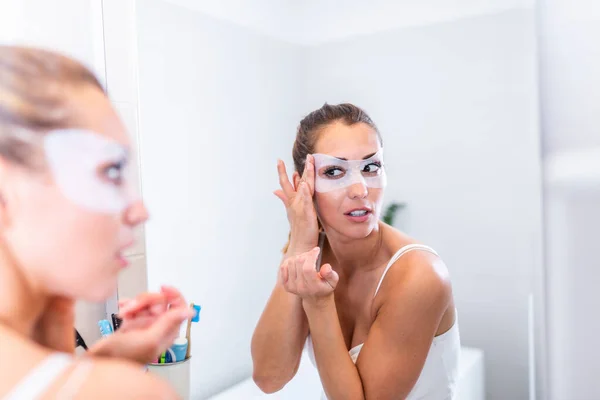 Frau Trägt Feuchtigkeitsspendende Maske Auf Gesicht Auf Schaut Badezimmerspiegel Mädchen — Stockfoto