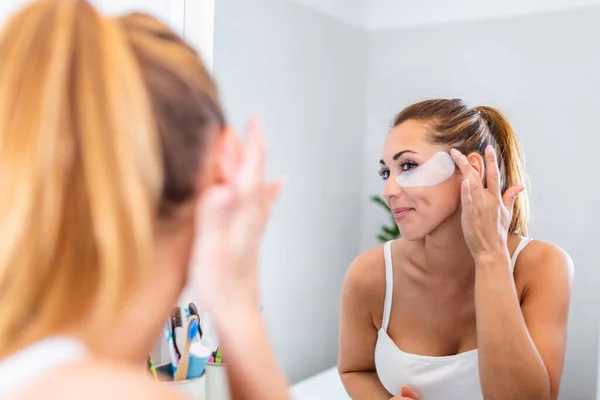 Beautiful Woman Applying Fatigue Eye Mask Looking Mirror Smiley Face — Foto de Stock