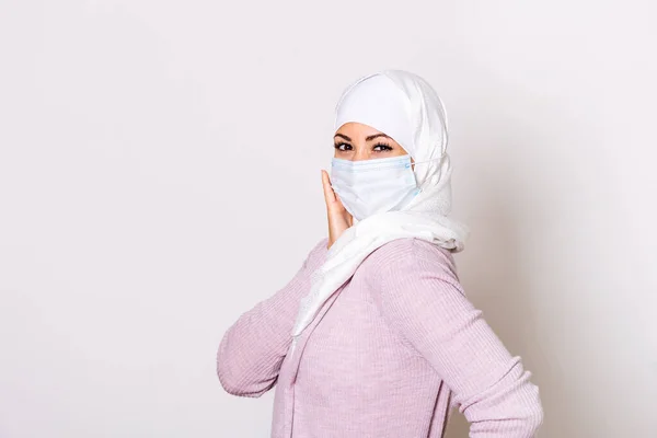 Muslim woman in respiratory mask. Masked woman with hijab putting on protective mask. Cold, flu, virus, tonsillitis, acute respiratory disease, quarantine, epidemic. Covid - 19, coronavirus prevention