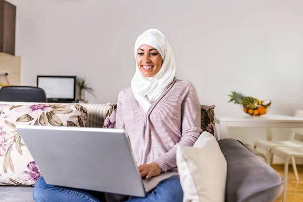 Szczęśliwa Muzułmanka Korzystająca Laptopa Siedząca Wygodnej Sofie Piękna Młoda Muzułmanka — Zdjęcie stockowe