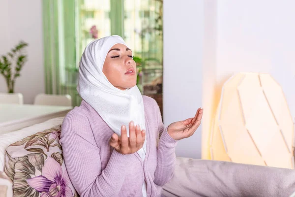 Young Woman Praying. Young Muslim woman praying, indoors. Young muslim woman in beige hijab and traditional clothes praying for Allah, copy space. Arab Muslim woman praying