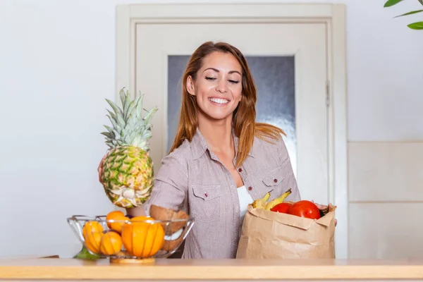 Portrait of beautiful young woman grocery shopping bag with vegetables at home. Young woman holding grocery shopping bag with vegetables Standing in the kitchen.