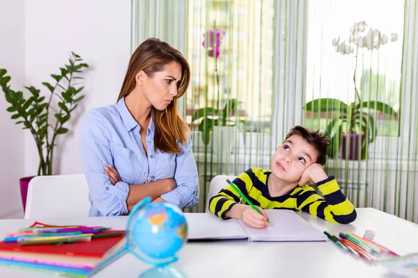 Stressed mother and son frustrated over failure homework, school problems concept. Sad little boy turned away from mother, does not want to do boring homework