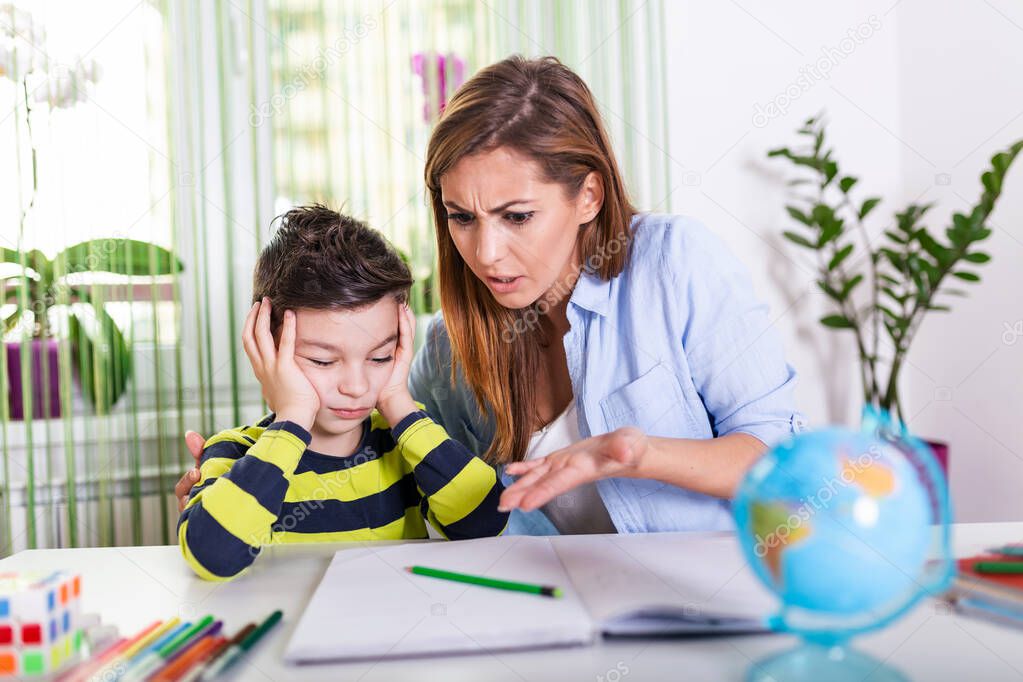 Do not ignore me when I am talking. Moms helping with homework. Mom is angry because her son dont want to do homework. Stressed mother and son frustrated over failure homework.