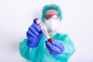 COVID-19, Corona Virüsü veya Roman Coronavirüs salgını. PPE 'de çalışan doktor veya laboratuvar teknisyeni, hastane laboratuvarında kan tüpü testi yapıyor.