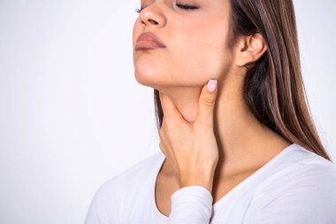 Young beautiful woman suffering from pain in throat, touching inflamed zone on her neck, cropped, empty space, sore throat